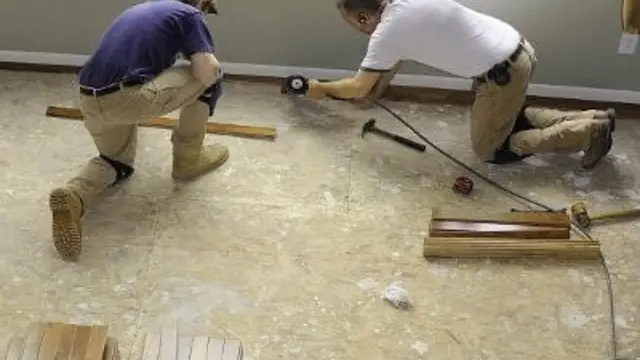 Two contractors kneeling on a subfloor while installing new flooring